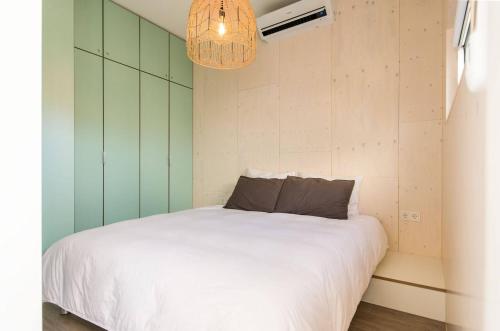a bedroom with a white bed and a chandelier at Cumbuco - Ecohuisjes Terschelling in Midsland