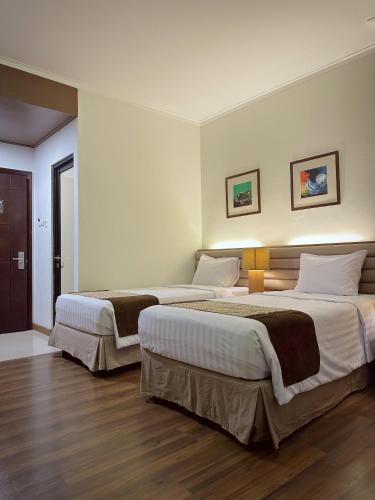 two beds in a hotel room with wood floors at Point C Hotel in Bandung
