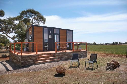 a tiny house with two chairs in a field at The Gums Cottage by Tiny Away in Hallett