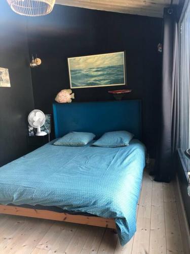 - une chambre dotée d'un lit bleu et d'une peinture murale dans l'établissement Les Cabines, à Sainte-Marie de Ré