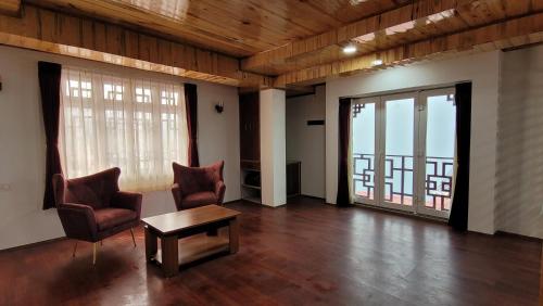 a living room with two chairs and a table at Rufina Greenland Premiere in Pelling