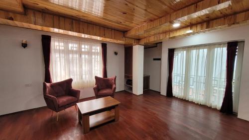 a living room with two chairs and a table at Rufina Greenland Premiere in Pelling
