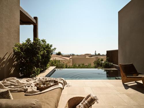 a backyard with a swimming pool with a couch and a chair at Pierros Verde in Lithakia