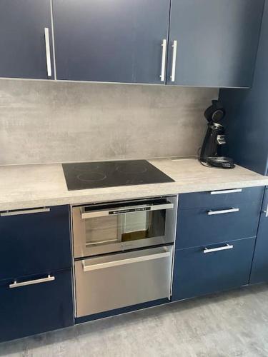 Il comprend une cuisine équipée d'une cuisinière et de placards bleus. dans l'établissement Charmant studio face mer - 2 personnes, à Le Touquet-Paris-Plage