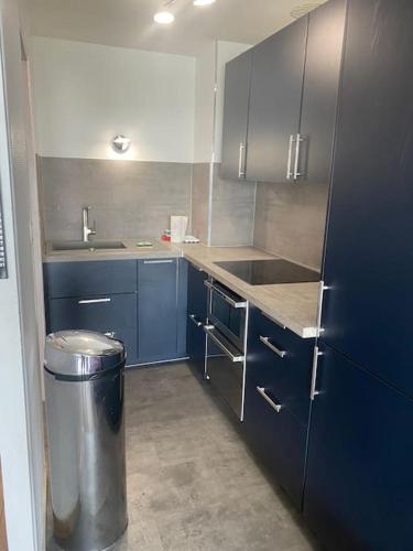 une cuisine avec des armoires bleues et une poubelle dans l'établissement Charmant studio face mer - 2 personnes, à Le Touquet-Paris-Plage
