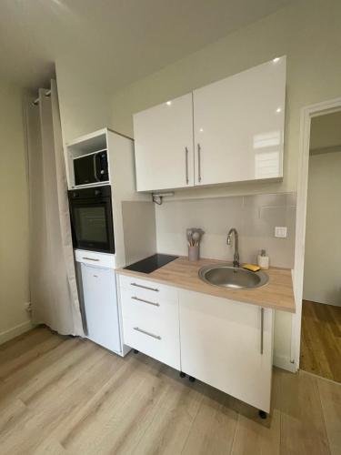 une cuisine avec des armoires blanches et un évier dans l'établissement Hypnos-Hébergement champenois, à Châlons-en-Champagne