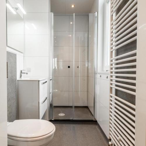 a white bathroom with a toilet and a shower at Biebosch - Garden house in Valkenburg