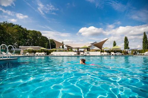 a woman swimming in a swimming pool with buildings in the background at Biebosch - Garden house in Valkenburg