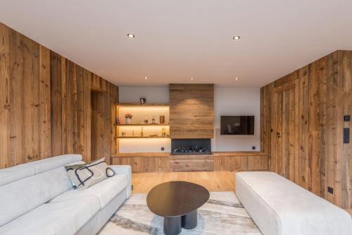 - un salon avec des murs en bois, un canapé et une table dans l'établissement Le Refuge contemporain - Welkeys, à Megève