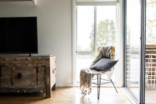a living room with a chair with a pillow on it at Orion Beach Cottage A - Jervis Bay in Vincentia