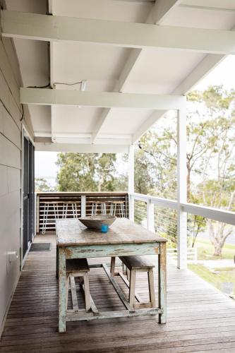 a wooden table on the porch of a house at Orion Beach Cottage A - Jervis Bay in Vincentia