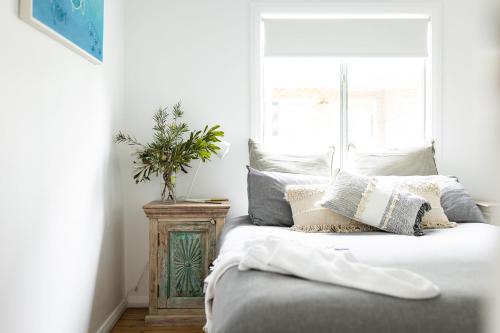 ein Schlafzimmer mit einem Bett mit Kissen und einem Fenster in der Unterkunft Orion Beach Cottage A - Jervis Bay in Vincentia
