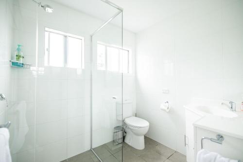 ein weißes Badezimmer mit Toilette und Dusche in der Unterkunft Orion Beach Cottage A - Jervis Bay in Vincentia