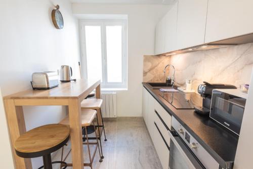 une cuisine avec une table et un comptoir dans l'établissement PREMIUM T2 neuf 1er étage ultra Centre Lorient par Groom, à Lorient