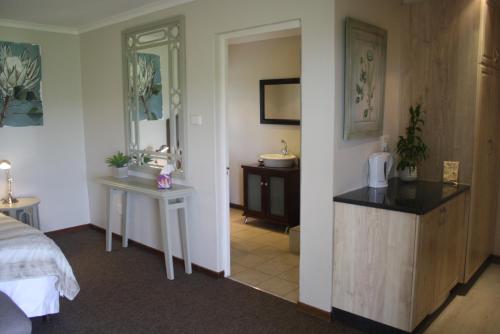 a bedroom with a bed and a bathroom with a sink at Elgin Guest House in Underberg