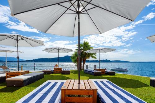 a picnic table with an umbrella next to the water at Resort Antico Verbano in Meina