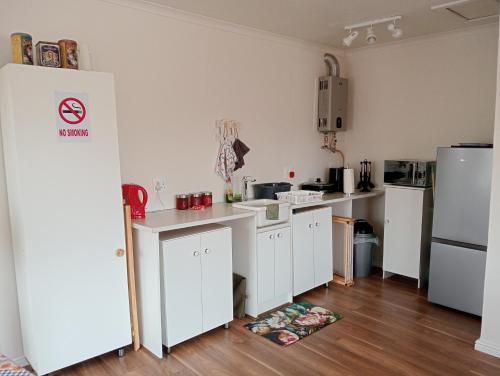 a kitchen with white cabinets and a refrigerator at The Wee Hoose in Strand