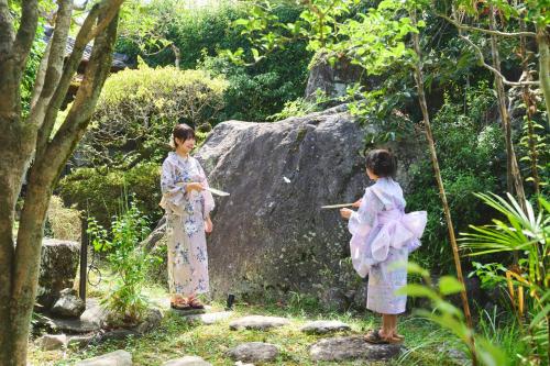 two girls in kimonos standing next to a rock at 温泉付きの一軒家を借りよう in Beppu