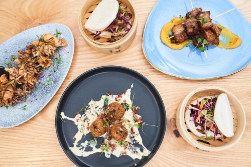 four plates of food on a wooden table at Hotel Olivewood in East London