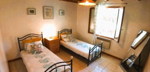 deux lits dans une petite pièce avec une fenêtre dans l'établissement Hortensia & Rose Gites, à Montpezat
