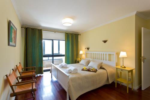 a bedroom with a bed with two chairs and a window at VIVA Belos Ares in Porto