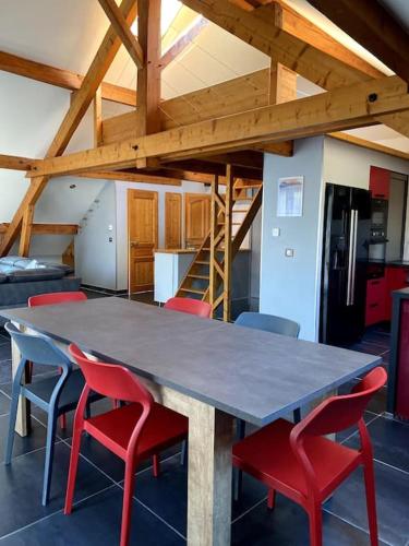 une grande table avec des chaises rouges dans une pièce dans l'établissement Montricher Karellis, à 5 min de Saint Jean de Maurienne, à Montricher-Albanne