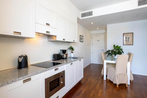a kitchen with white cabinets and a table and chairs at Resort Antico Verbano in Meina