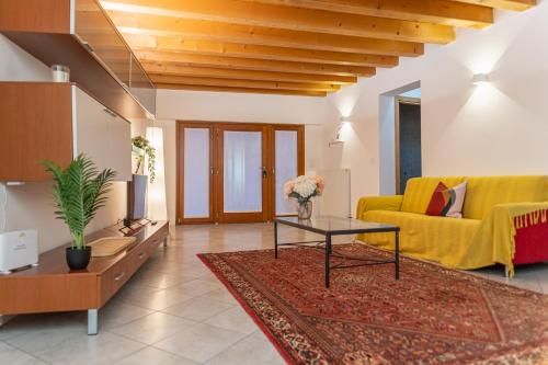 a living room with a yellow couch and a table at NEST LIVING Sunset 42 in Udine