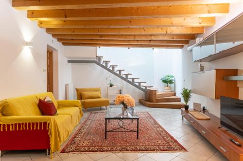 a living room with a yellow couch and a table at NEST LIVING Sunset 42 in Udine