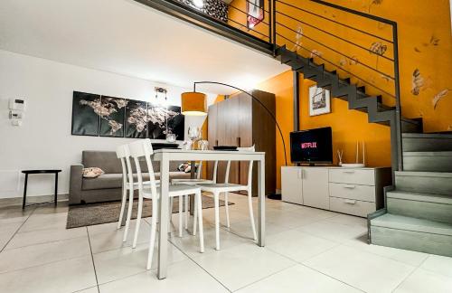 a living room with a table and chairs and a staircase at Loft Stadio - Parking, Gym & Comfort in Turin