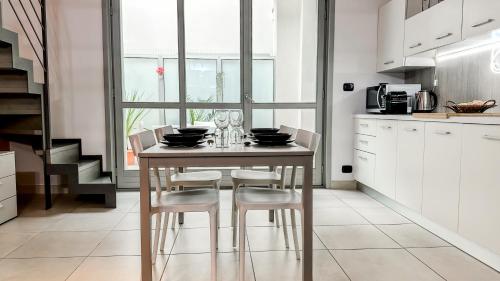 a kitchen with a wooden table with chairs and a kitchen with white cabinets at Loft Stadio - Parking, Gym & Comfort in Turin