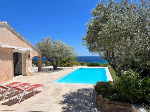 une piscine avec deux chaises et une maison dans l'établissement Villa vue mer panoramique, à Sainte-Maxime