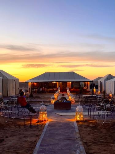 a group of tents with lights in the sunset at Merzouga Glamping With AC in Merzouga