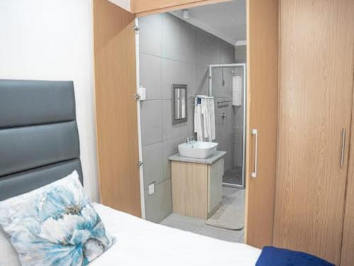 un bagno con un letto, un lavandino e uno specchio di 196 On Victoria Bed & Breakfast a Newcastle
