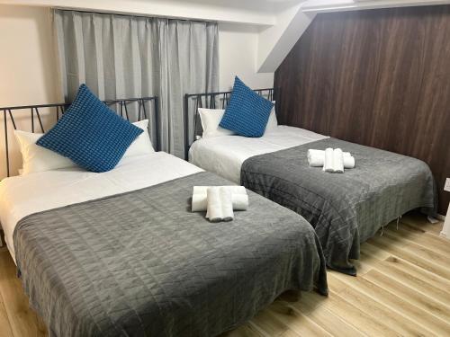 two beds in a hotel room with blue pillows at Ikebukuro Area R2 NishiikeApartment 5F No Elevator in Tokyo