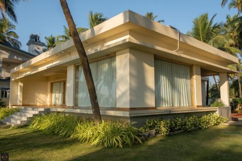 a house with a palm tree in front of it at Reunion Ocean Elite - Beach House in Udupi