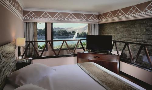 a bedroom with a bed and a window with a television at Mövenpick Resort Aswan in Aswan