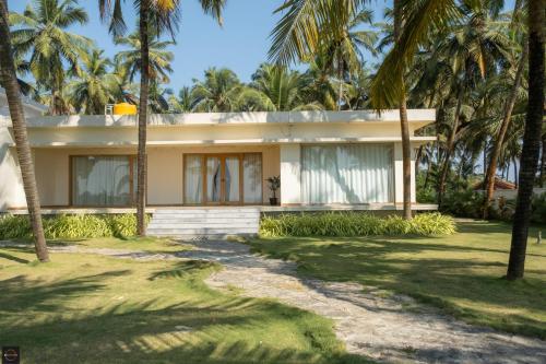 a house with palm trees in front of it at Reunion Ocean Elite - Beach House in Udupi