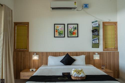 a bedroom with a bed with two tables and two windows at Reunion Ocean Elite - Beach House in Udupi