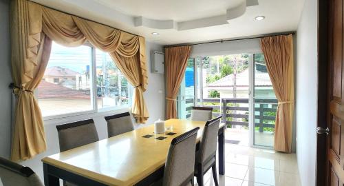 a dining room with a table and chairs and a large window at Purepamvillage in Kata Beach