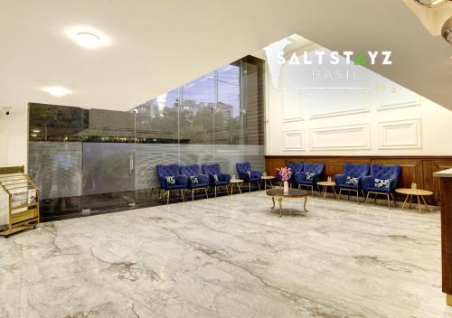 a lobby with blue chairs and a table in a building at Saltstayz Basil - Near Golf Course Road & Extension Road in Gurgaon