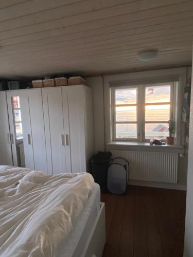a bedroom with a white bed and a window at Ilulissat Stay - Seawatch Retreat in Ilulissat