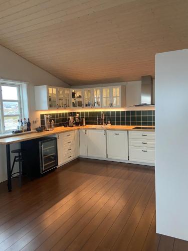 a large kitchen with white cabinets and a wooden floor at Ilulissat Stay - Seawatch Retreat in Ilulissat