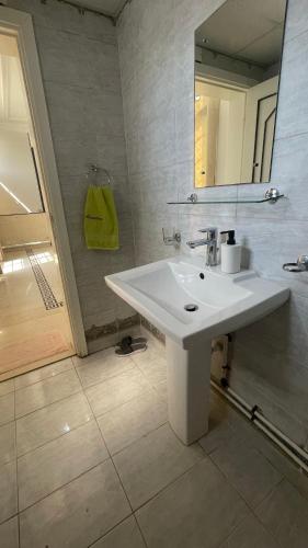 a white bathroom with a sink and a mirror at Arabian Nights Nook in Muscat