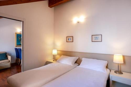two beds in a room with two lamps and a mirror at Resort Antico Verbano in Meina