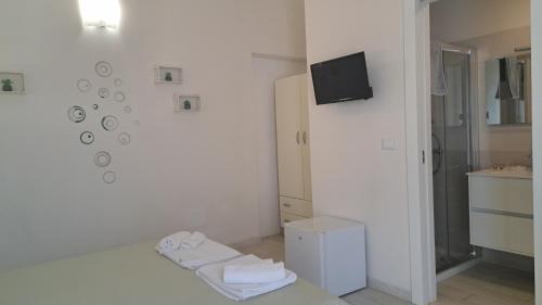 a bathroom with white walls and a tv on a wall at Giardino D'Oriente in Otranto