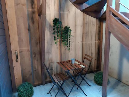 une petite table et des chaises à côté d'un mur en bois dans l'établissement Apt Robec, à Rouen