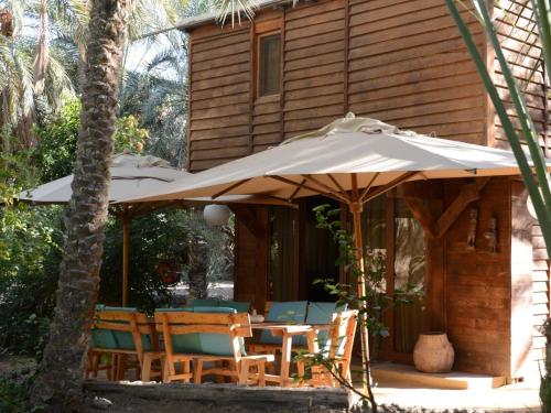 a table and chairs under an umbrella on a patio at Diar Abou Habibi in Tozeur