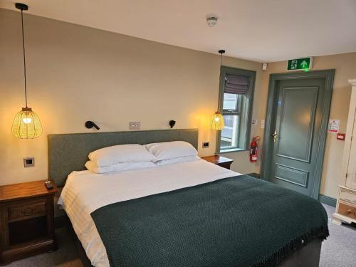 a bedroom with a large bed with a green blanket at Bushmills Townhouse in Bushmills