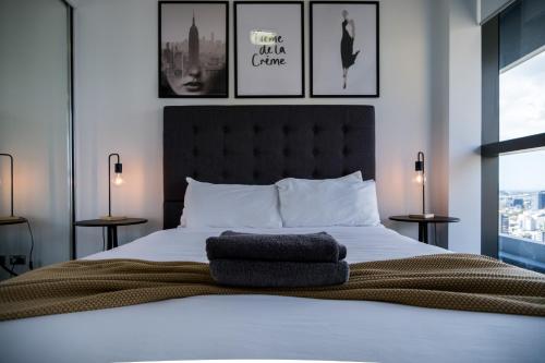 a bedroom with a bed with a black headboard and pictures at Infinity Tower Brisbane City in Brisbane